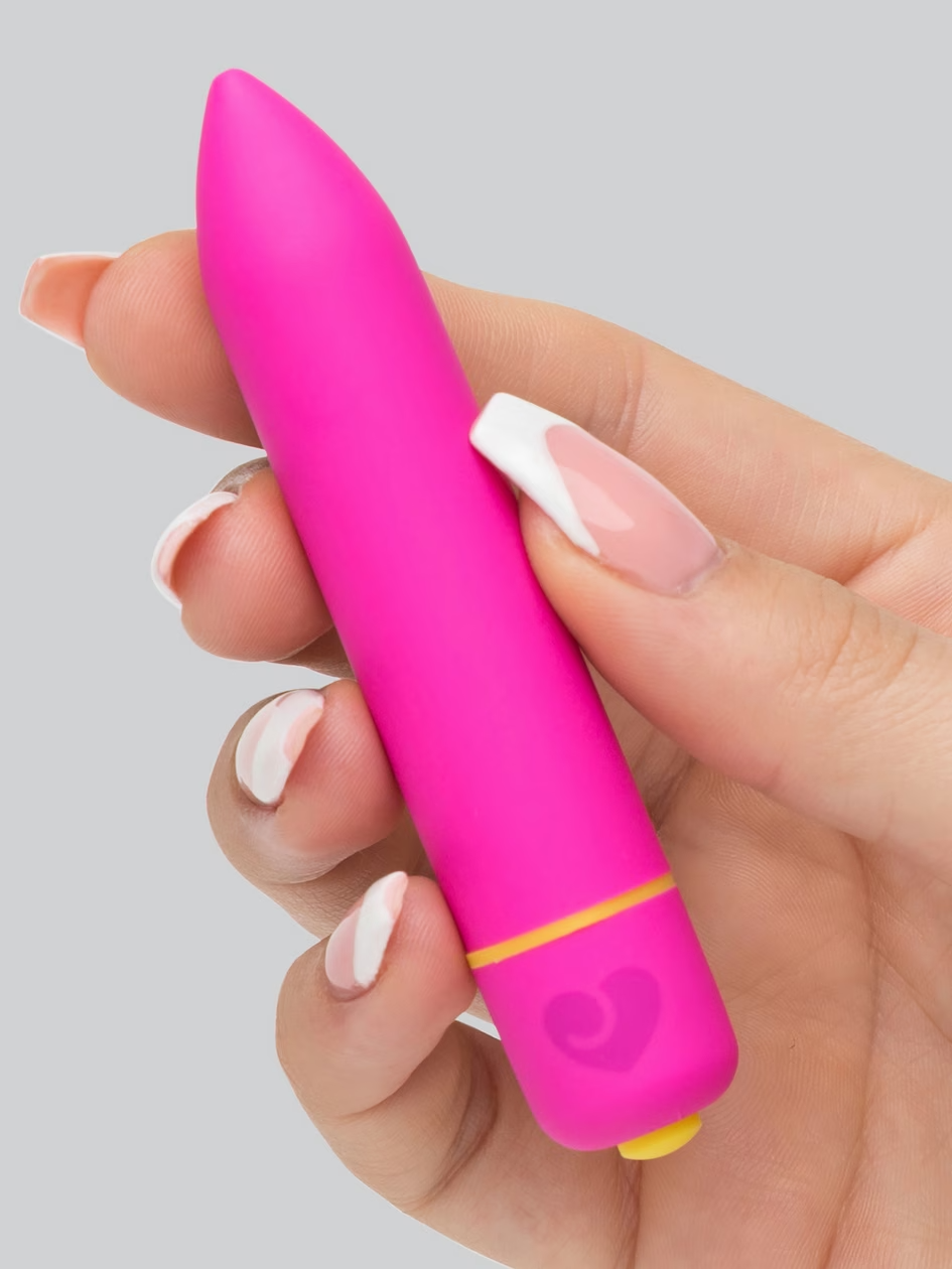 Hand holding a pink and yellow object against a gray background