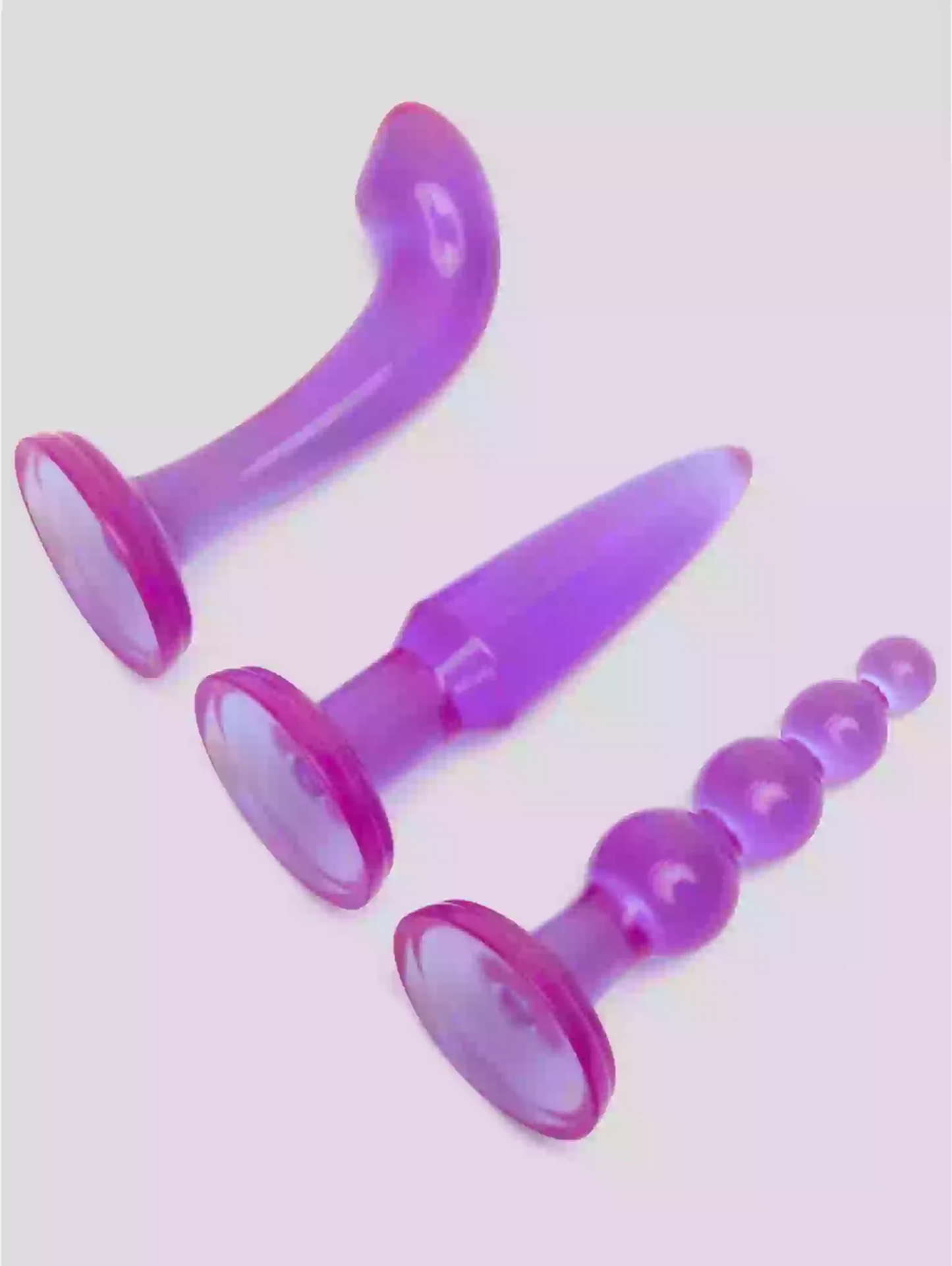 Set of purple silicone butt plugs on a white background