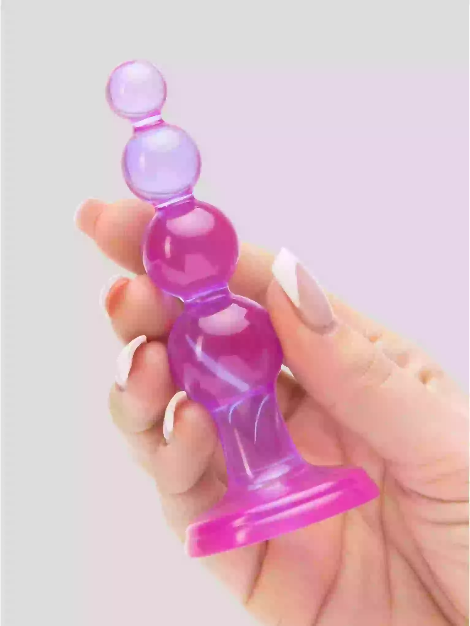 Hand holding a pink and purple silicone product against a light gray background