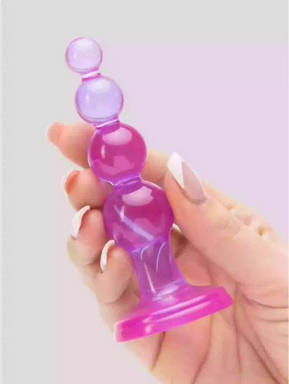 Hand holding a pink and purple silicone product against a light gray background