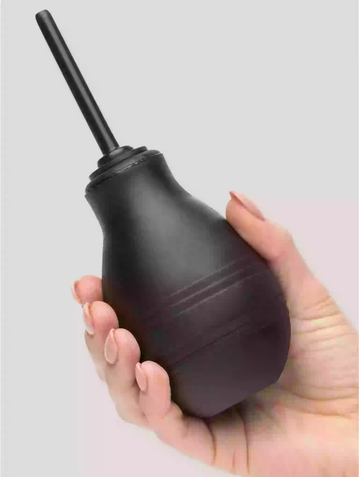 Black rubber bulb syringe held in a hand against a light gray background