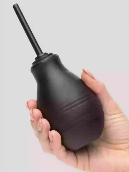 Black rubber bulb syringe held in a hand against a light gray background