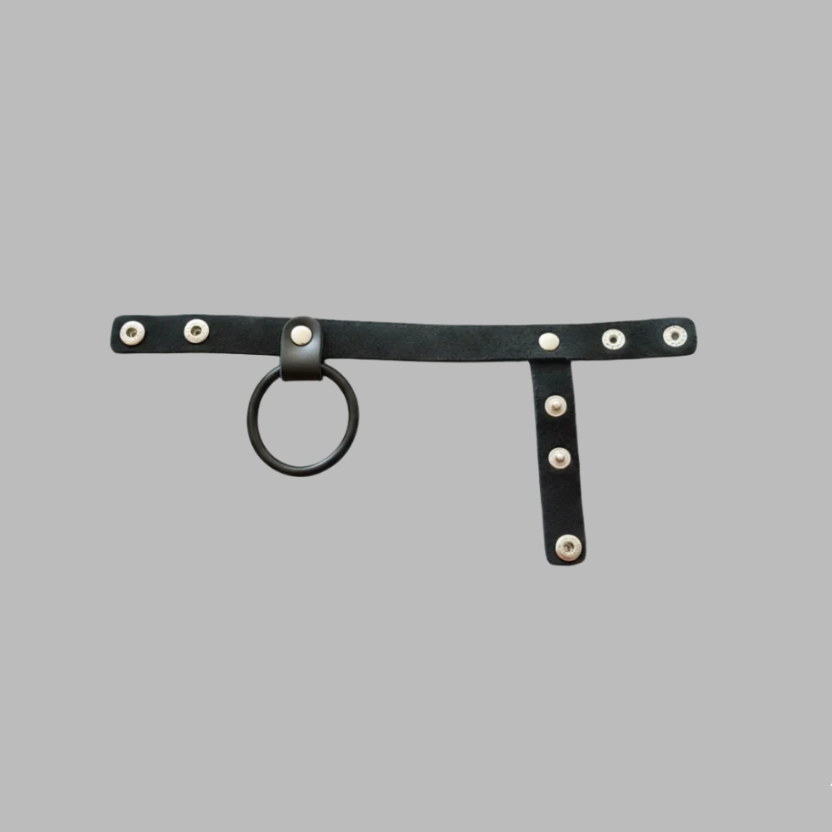 Black leather harness with metal rings and studs on a gray background