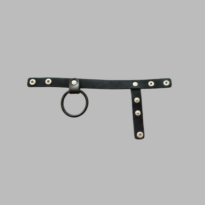 Black leather harness with metal rings and studs on a gray background