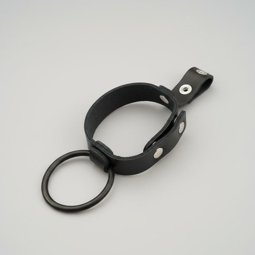 Black leather restraint with metal rings on a gray background