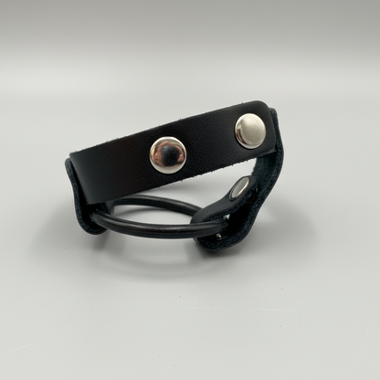 Black leather bracelet with silver buttons on a light gray background