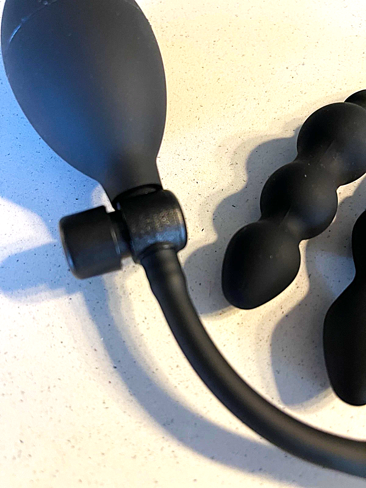 Black massage tool with rounded ends on a light surface