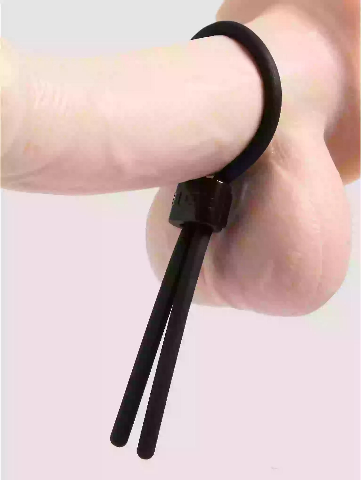 Black hair tie being worn on a wrist with a plain background