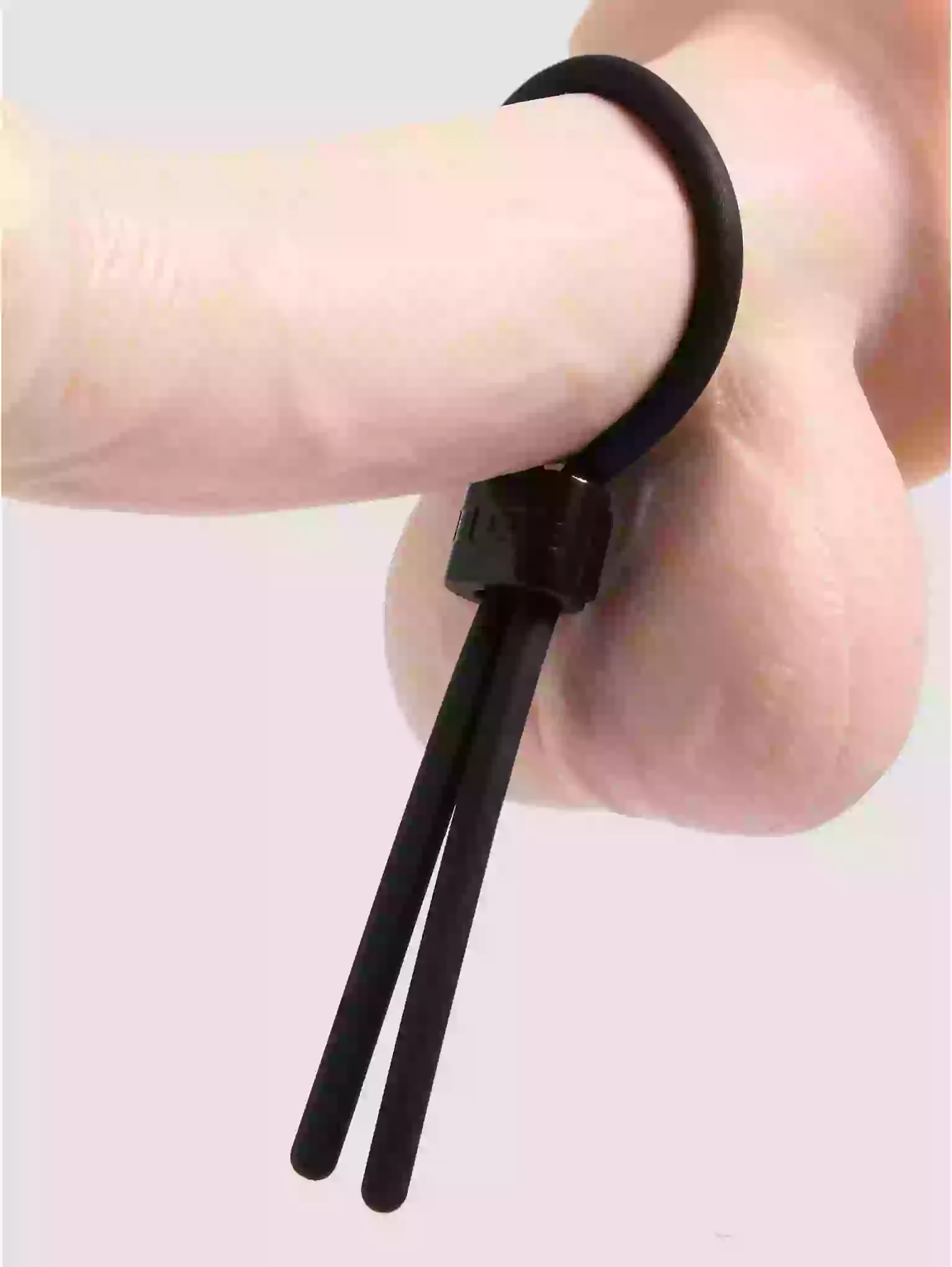 Black hair tie being worn on a wrist with a plain background