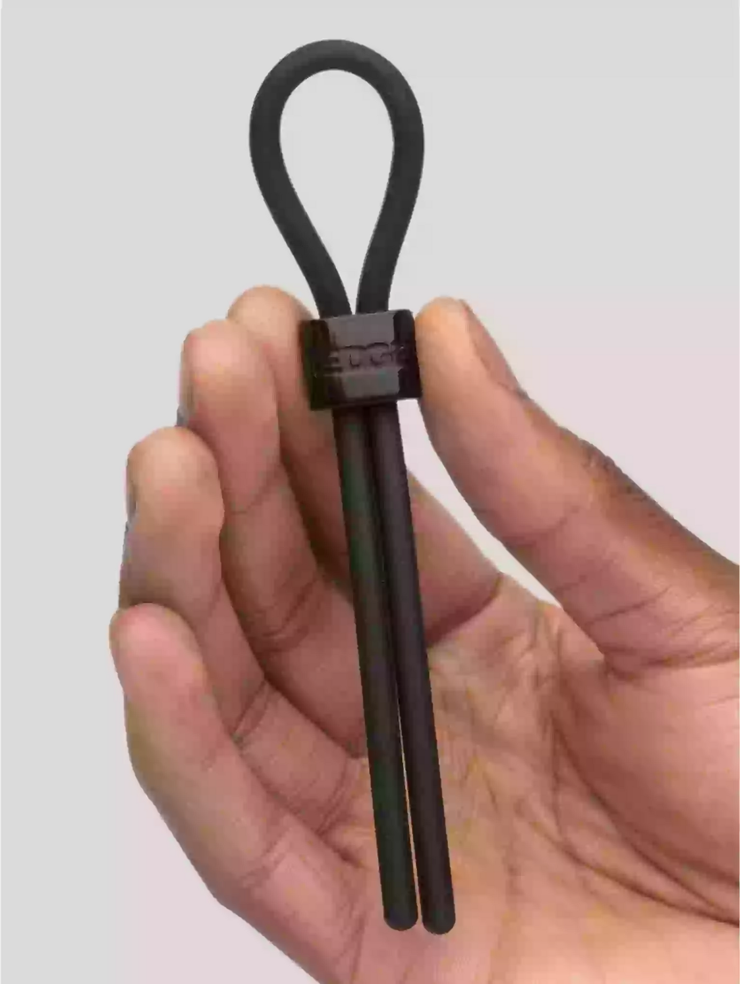 Hand holding a black metal tool with a loop handle against a light gray background