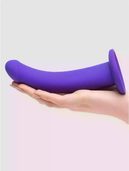 Purple silicone product held in a hand against a light gray background