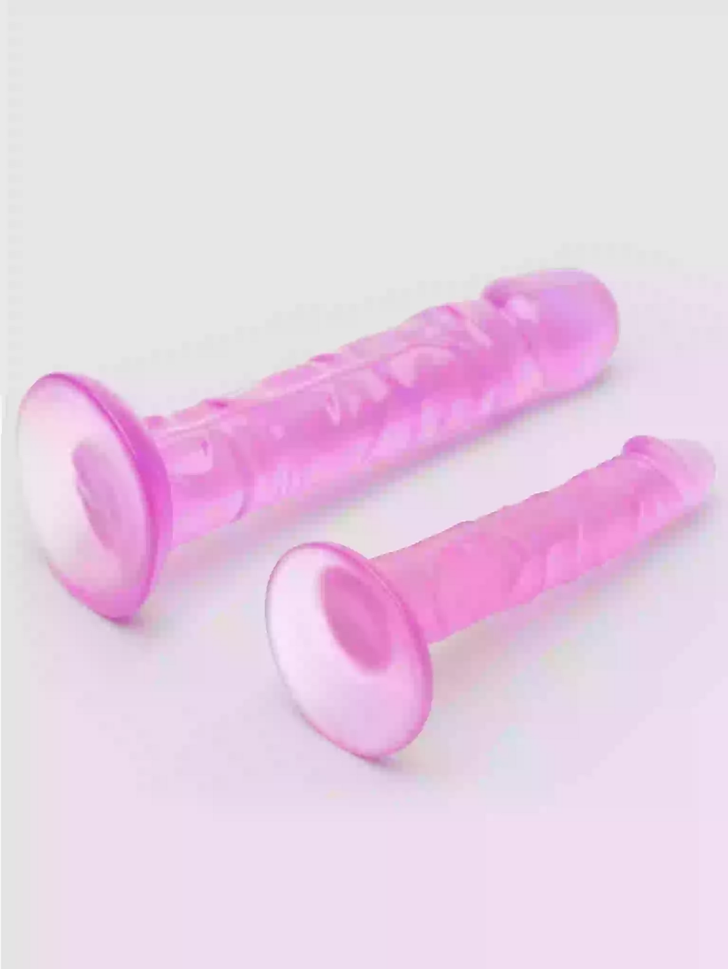 Two pink silicone dildos on a light gray background