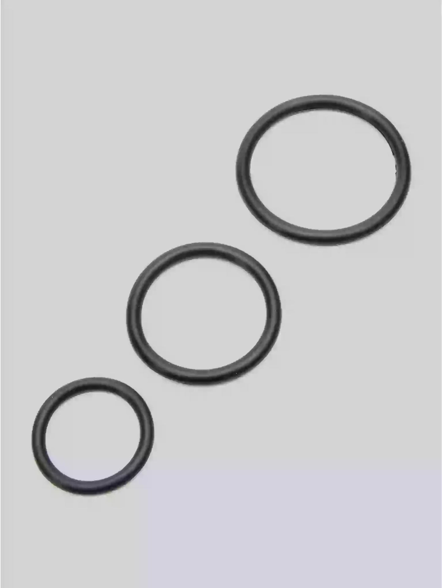 Three black rubber o-rings on a light gray background
