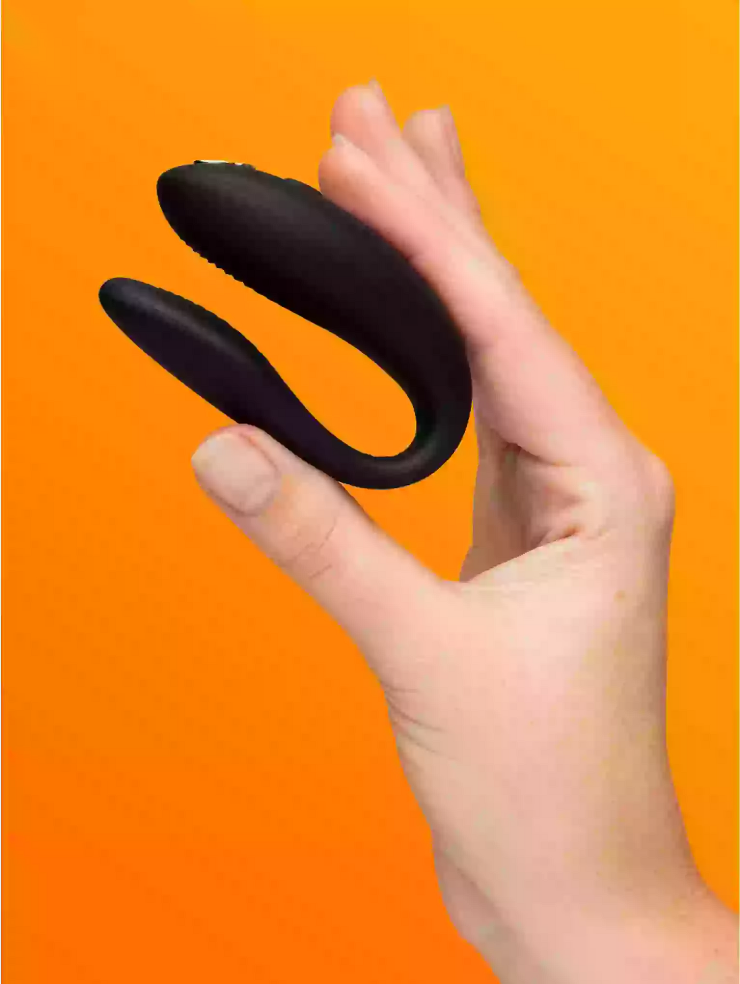 Black S-shaped object held in a hand against an orange background