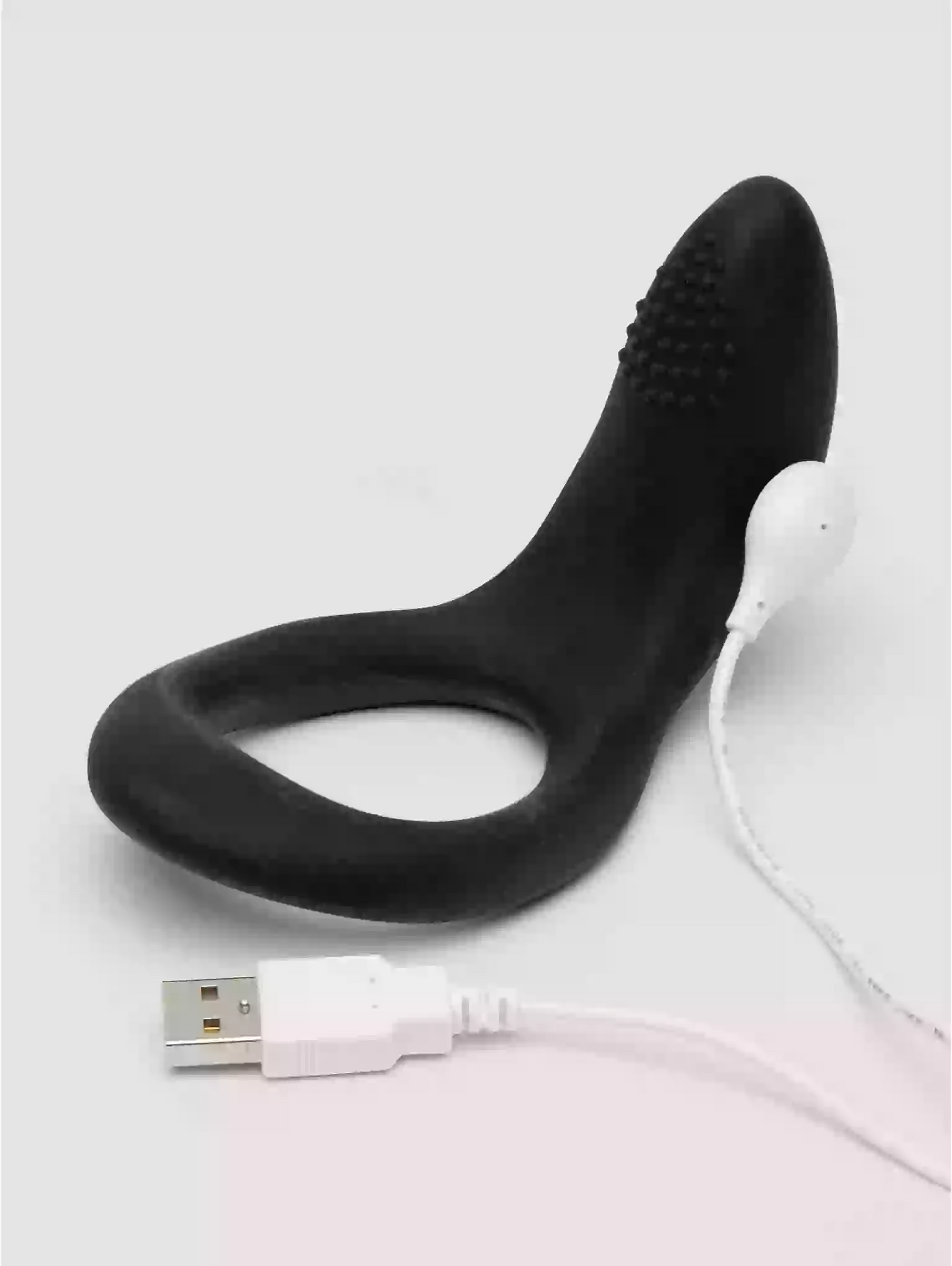 Black silicone ring with bristles and USB cable on a light gray background