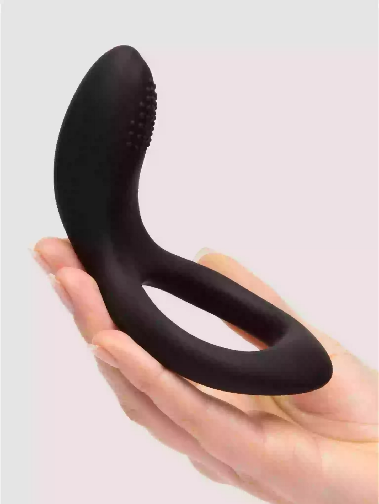 Black silicone butt plug held in a hand against a light gray background