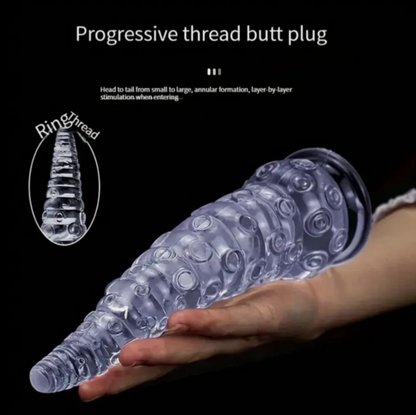 Clear progressive thread butt plug held by a hand on a black background with text.
