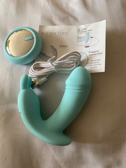 Turquoise and gold sex toy with packaging on a beige surface