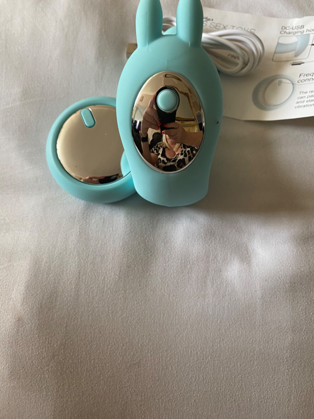 Turquoise rabbit-shaped device with a reflective surface on a light gray background