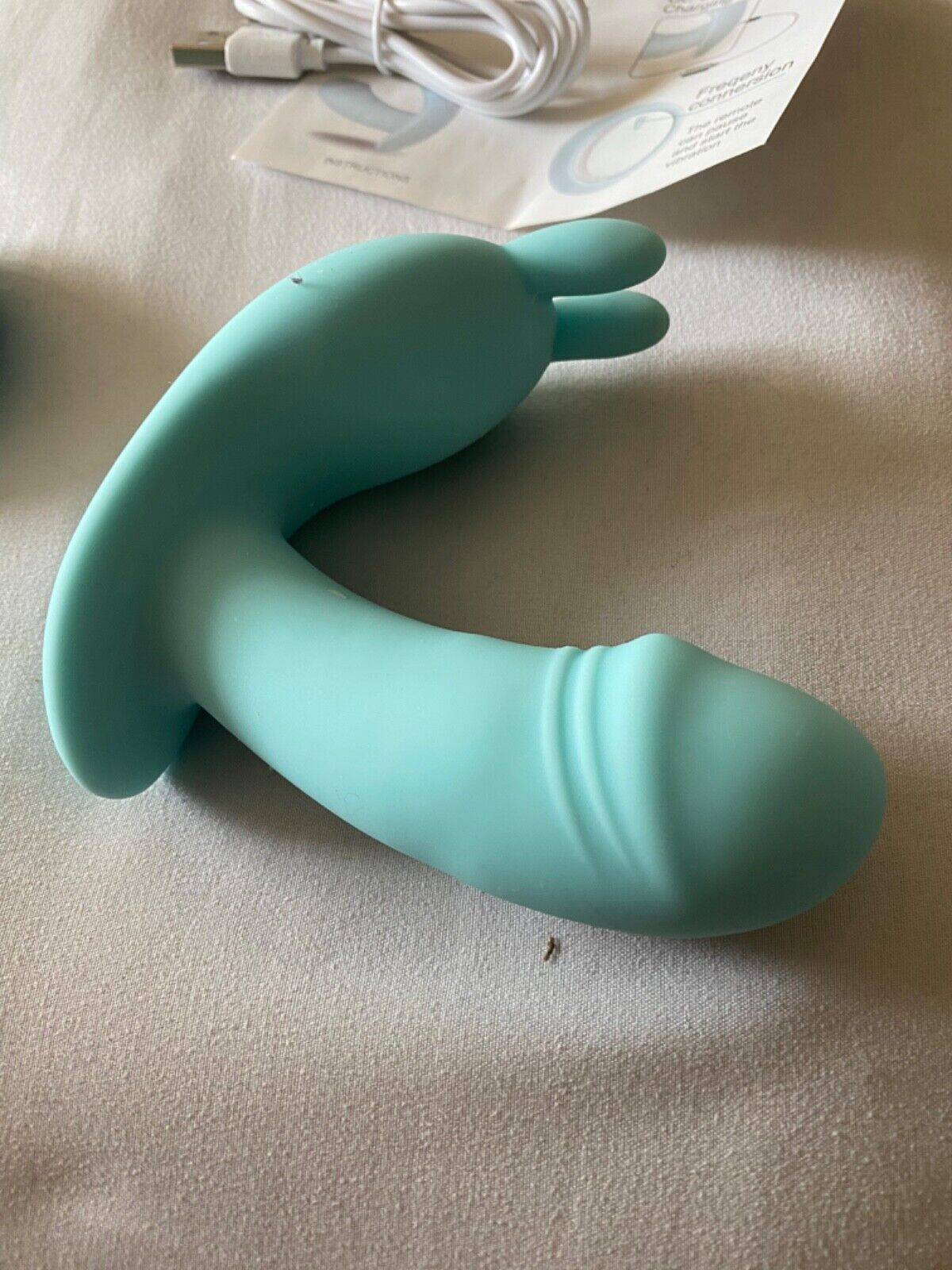 Turquoise silicone product on a beige surface with packaging in the background