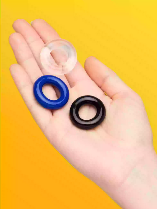 Three rubber washers (clear, blue, black) held in a hand against a yellow background