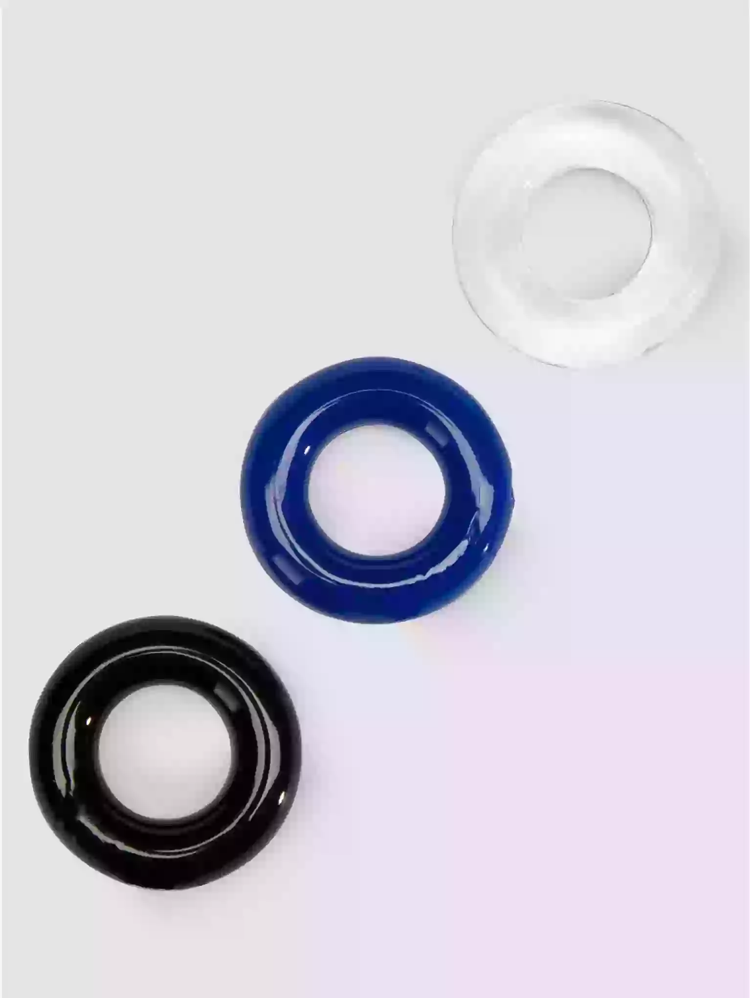 Three circular objects in black, blue, and clear on a white background