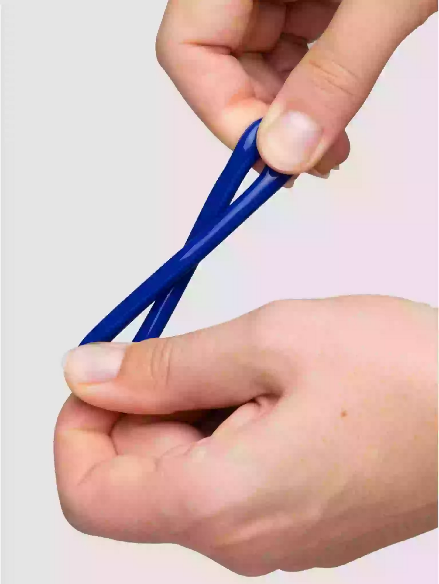 Hands holding a blue hair tie against a light gray background