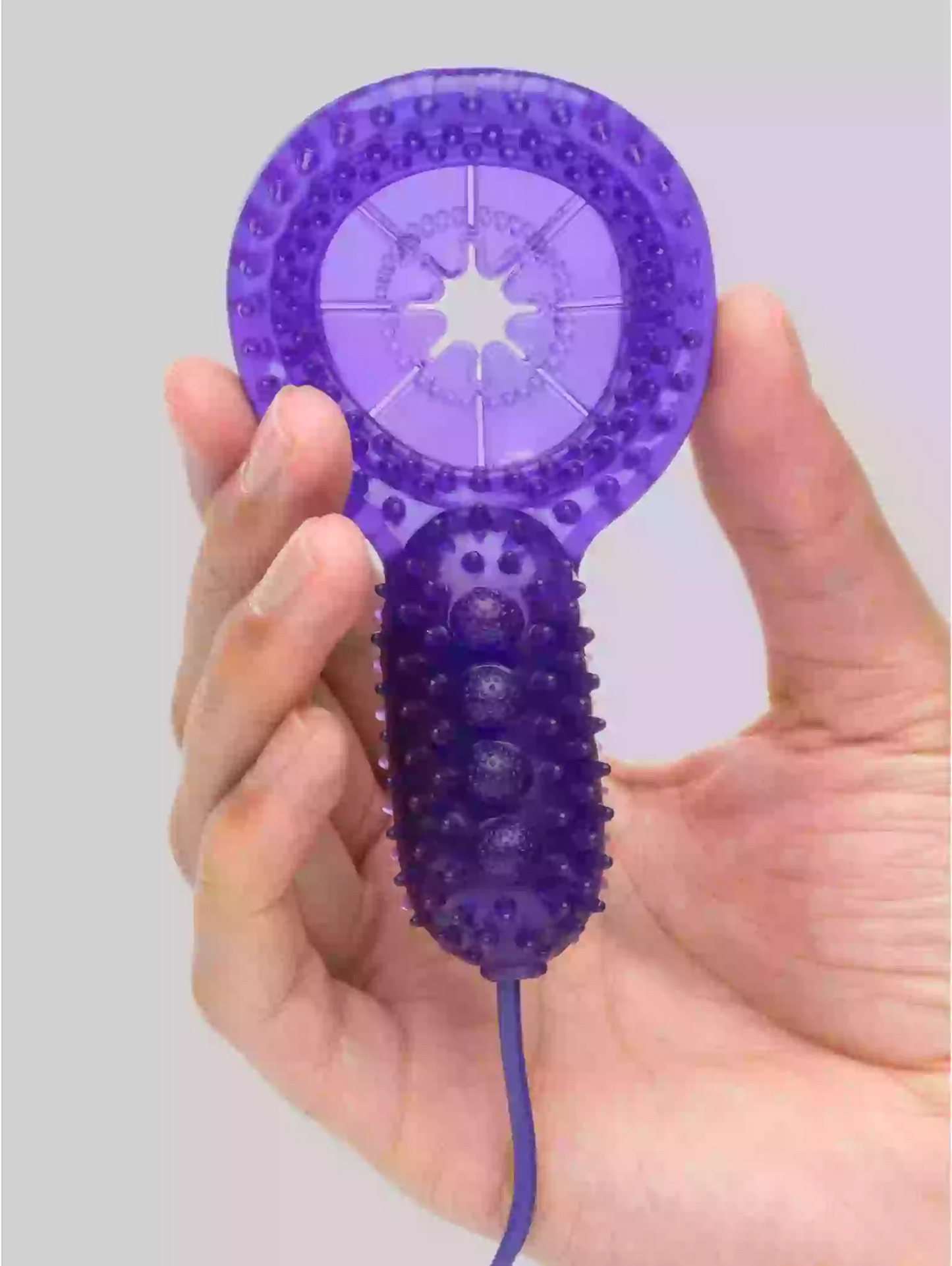 Purple handheld device with textured surface and star design held in a hand against a light gray background