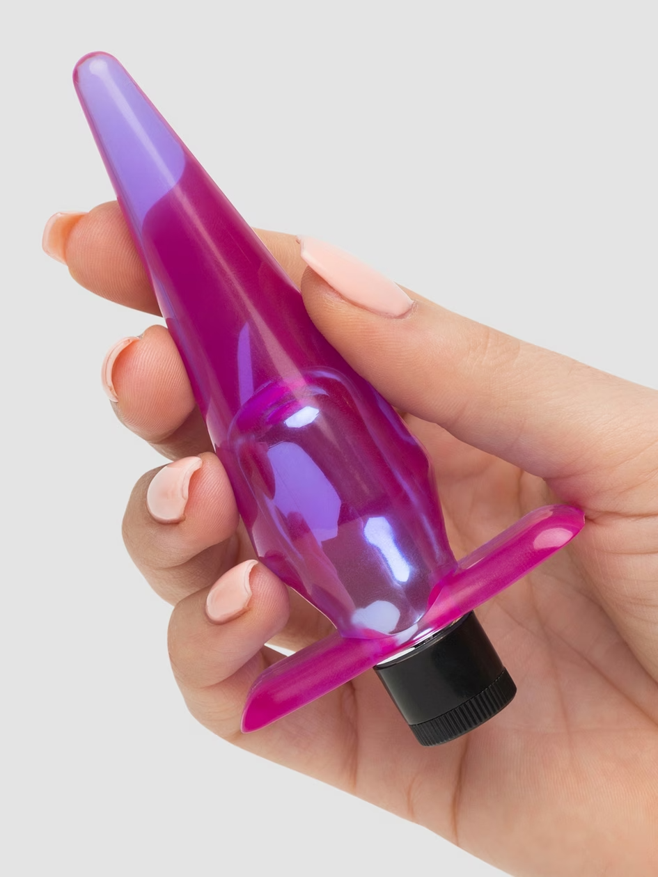 Hand holding a pink and purple bottle with a black cap against a light gray background
