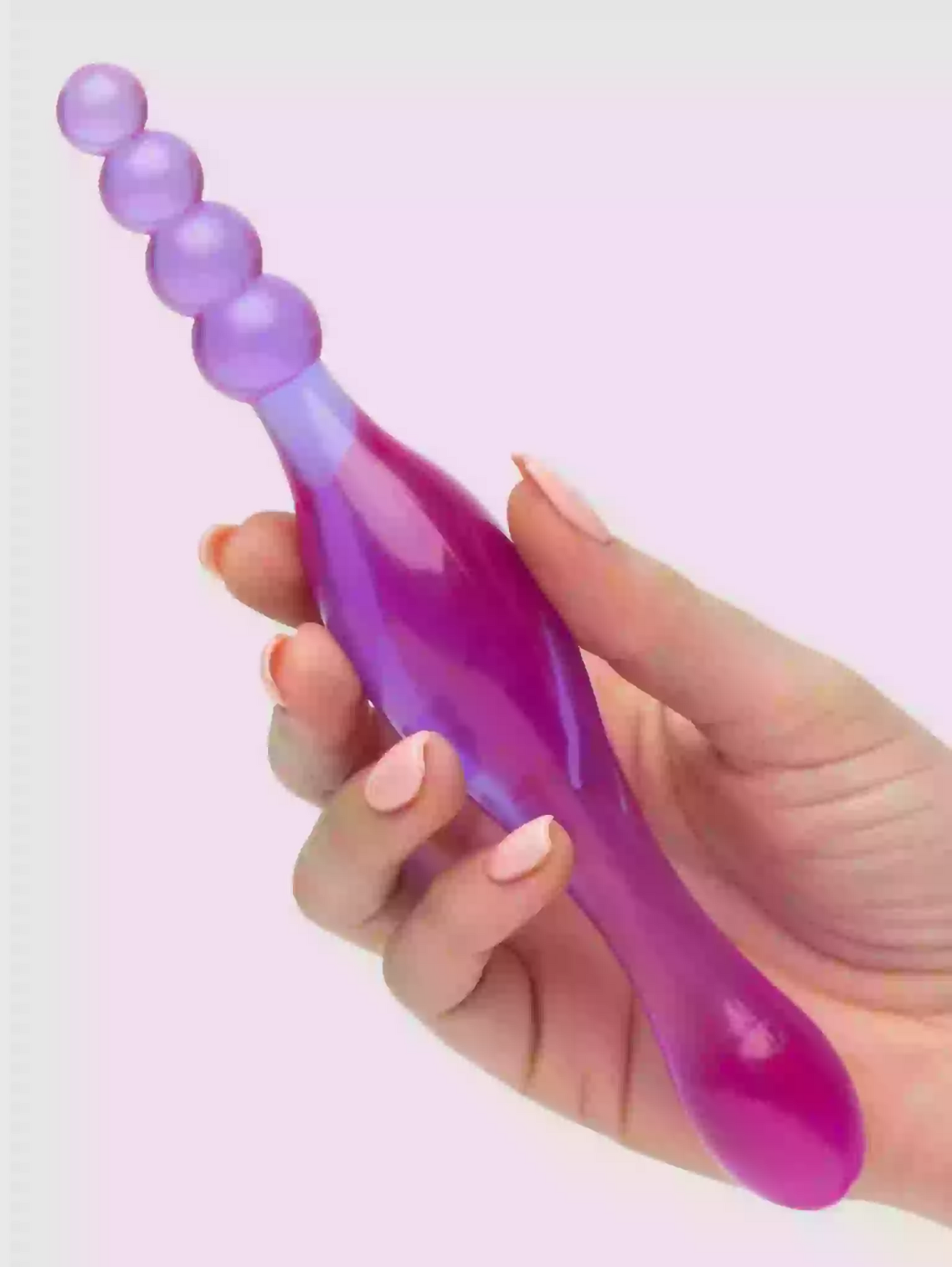 Purple and pink handheld massager held by a hand on a light purple background