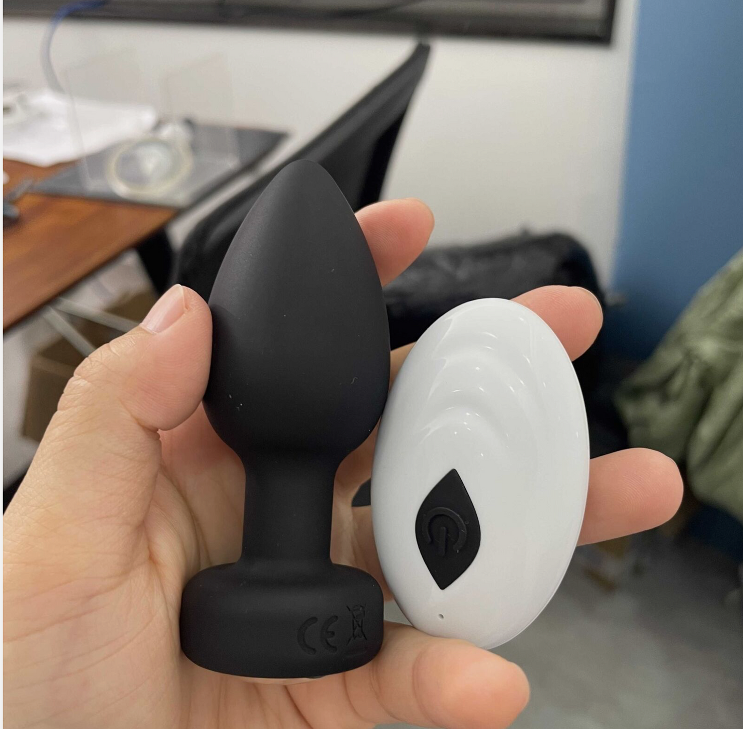 Hand holding a black and white silicone product with a blurred indoor background