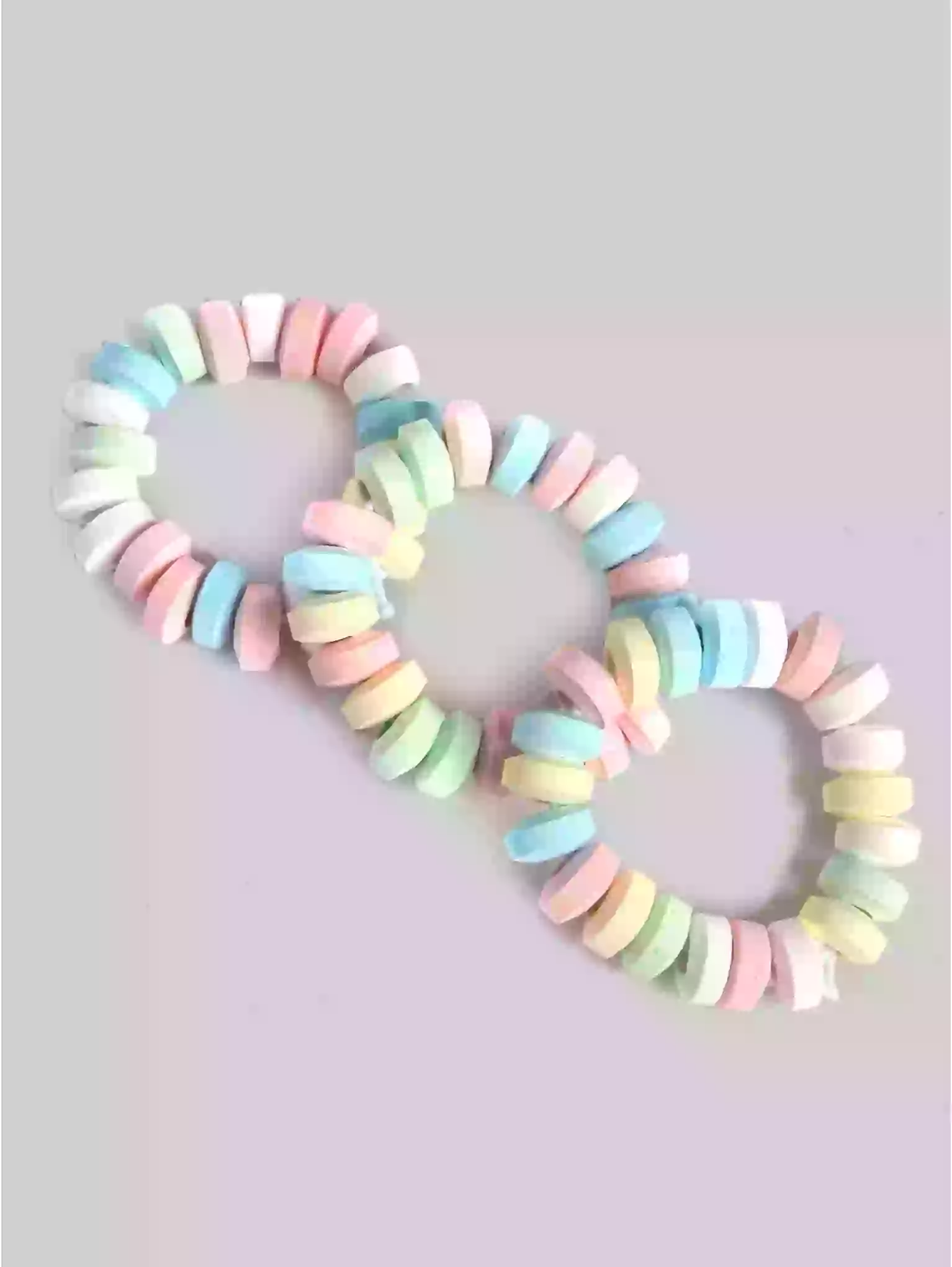 Pastel-colored hair ties arranged in a heart shape on a light gray background