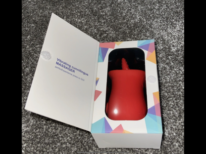 Red vibrator in a colorful box on a gray surface