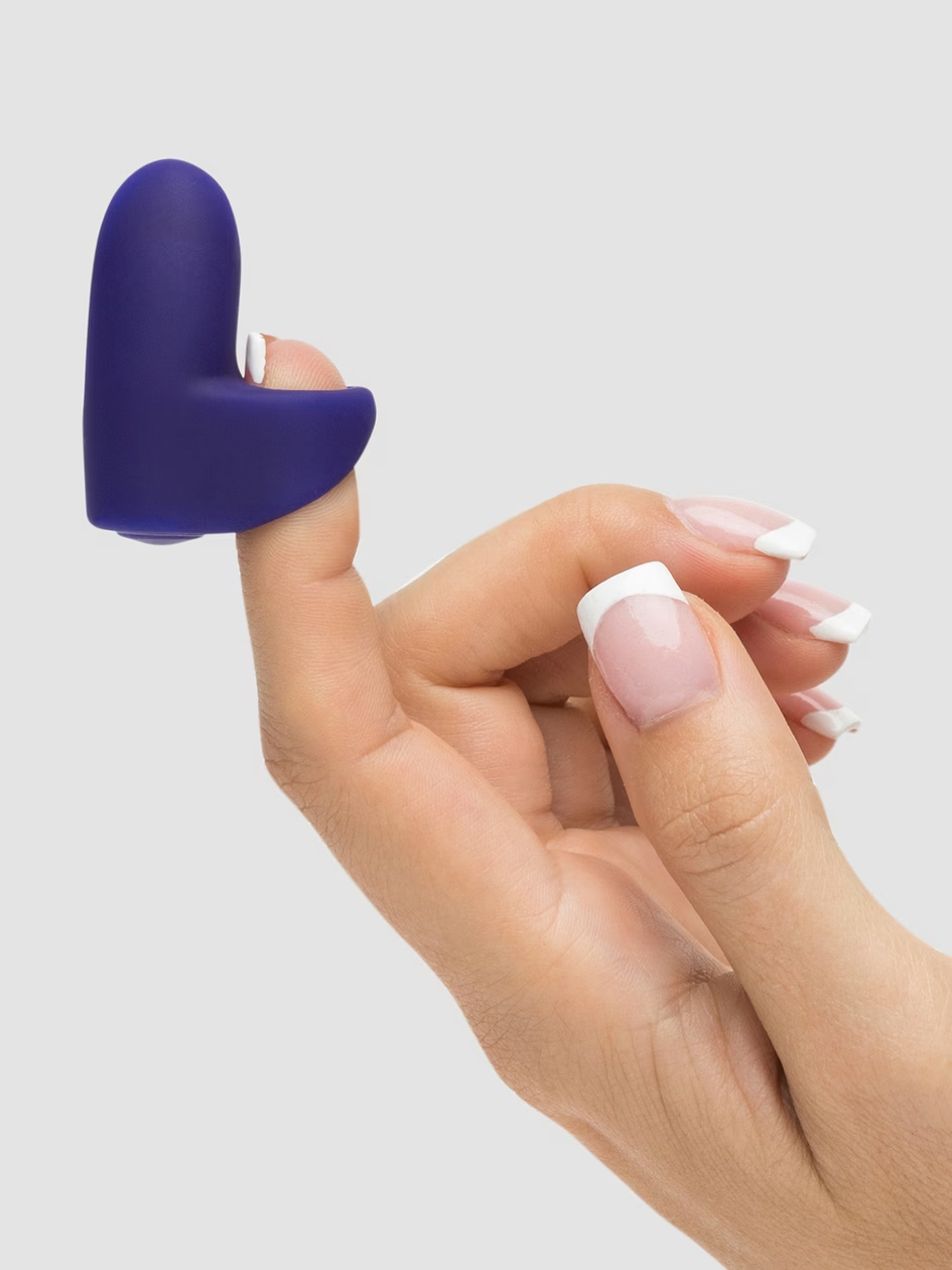 Hand holding a purple heart-shaped object against a light gray background