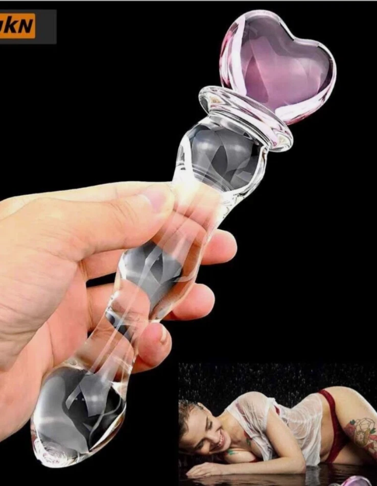 Glass heart-shaped object held by a hand with a black background