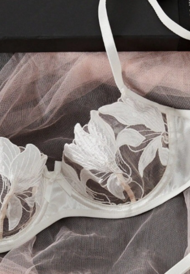White lace bra with floral embroidery on a dark background