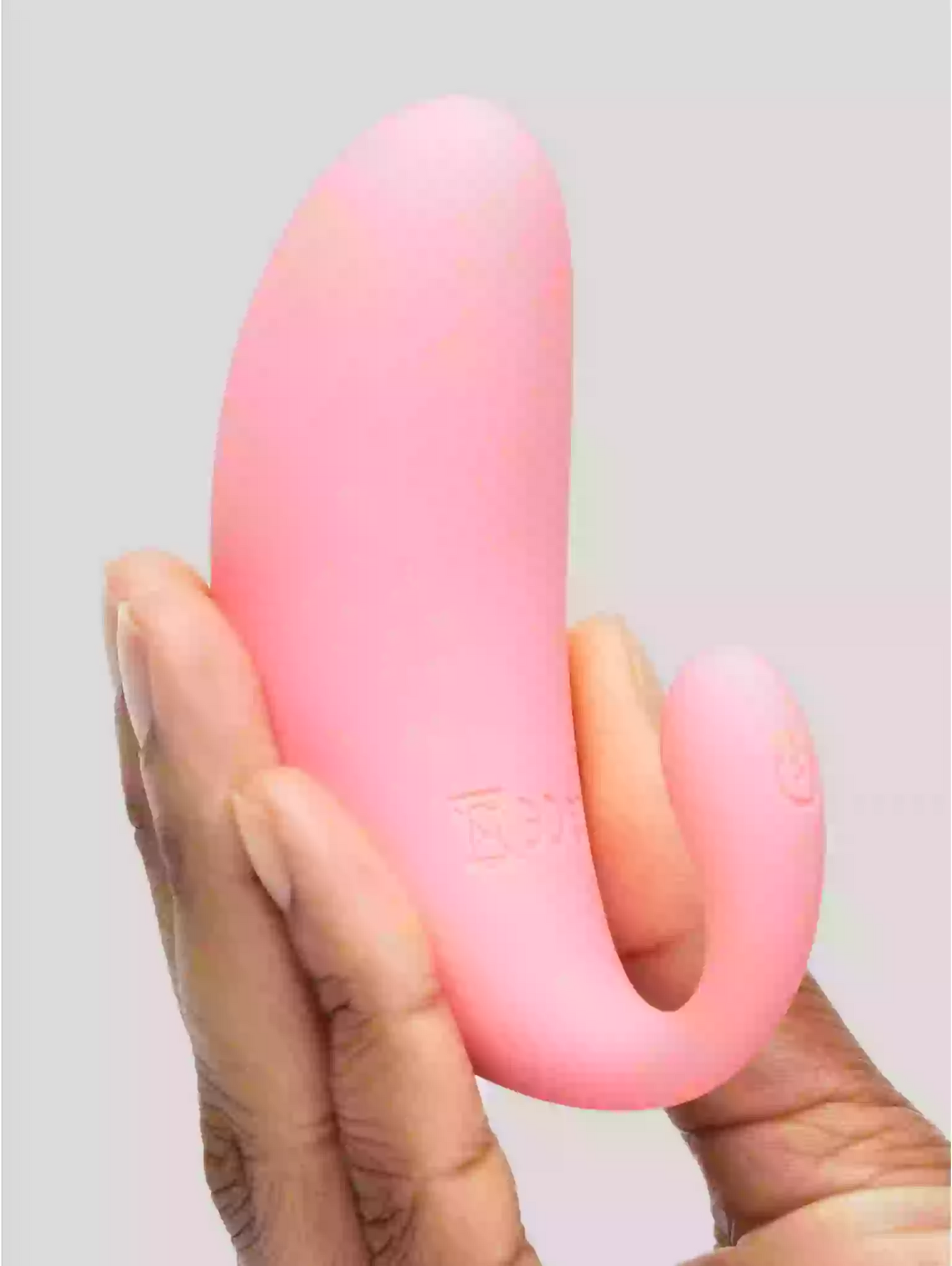 Pink and orange silicone tool held in a hand against a gray background