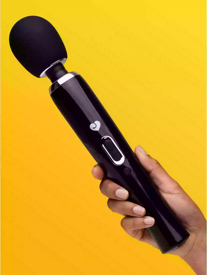 Hand holding a black handheld device against a yellow background