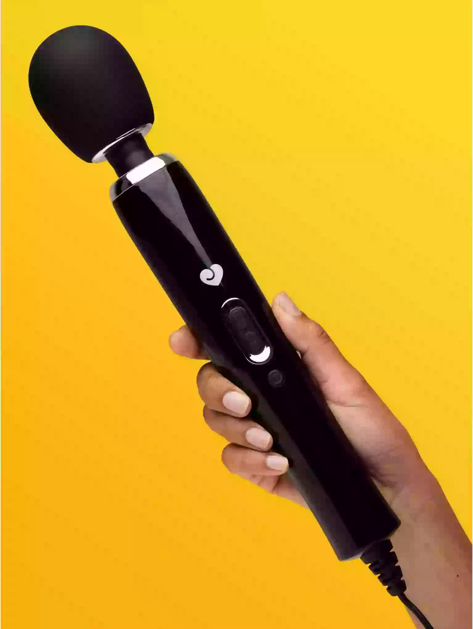 Black handheld device held by a hand against a yellow background
