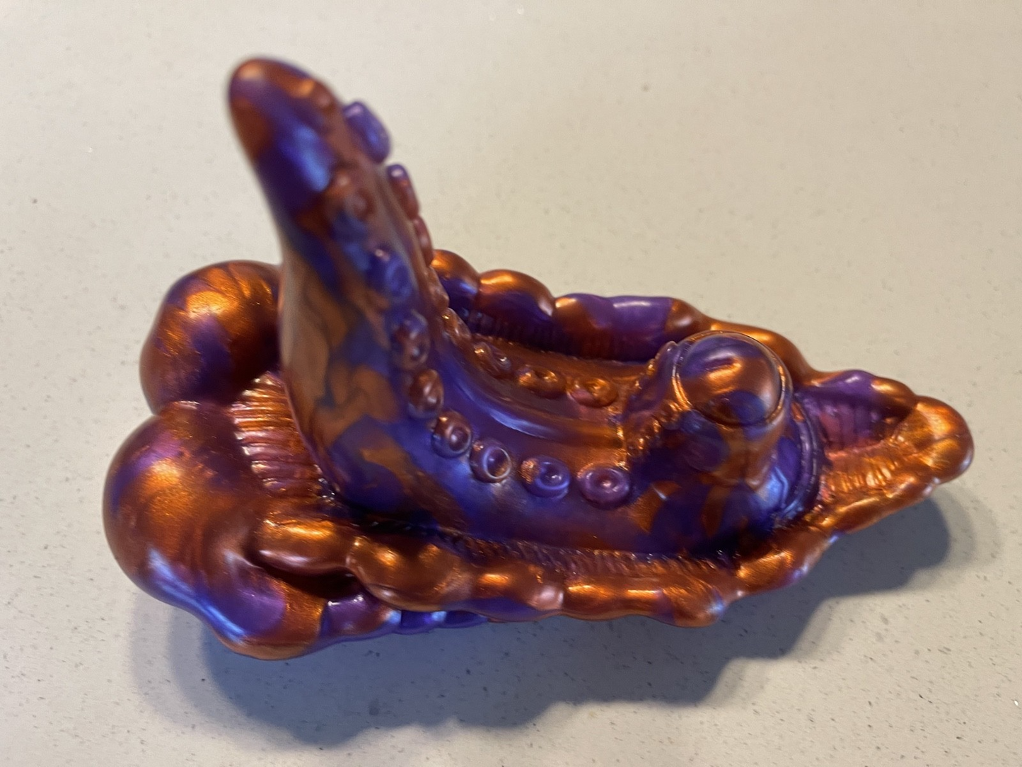 Decorative item resembling a stylized octopus with purple and gold colors on a light gray background