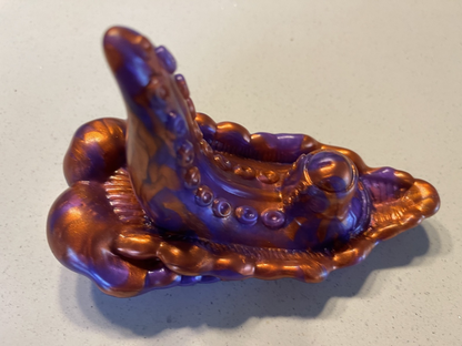 Decorative item resembling a stylized octopus with purple and gold colors on a light gray background