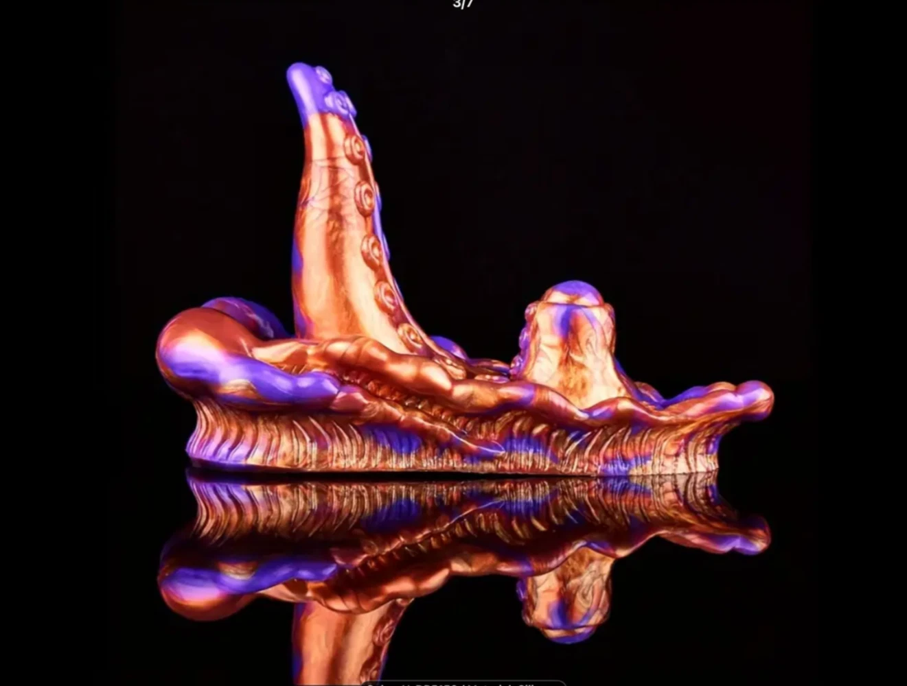 Copper-colored sculpture of a reclining figure on a reflective surface with a black background