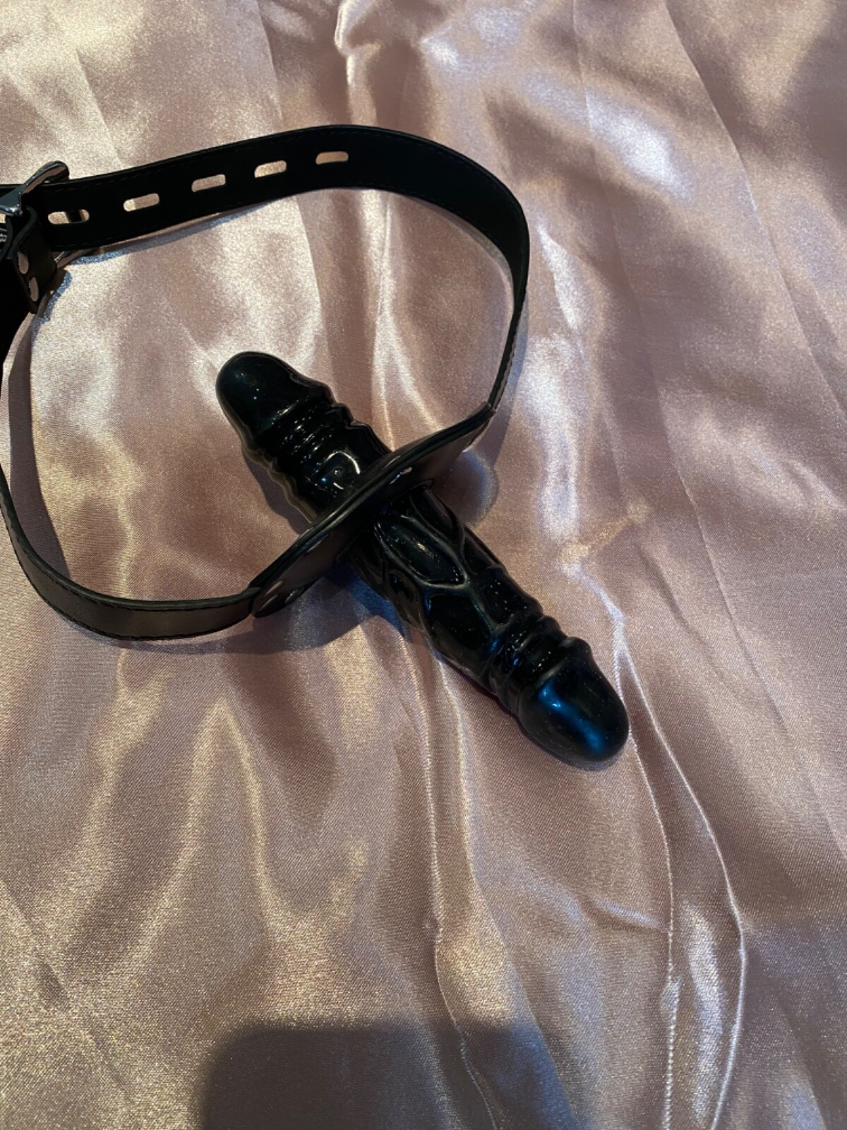 Black leather belt with a clasp on a light fabric background