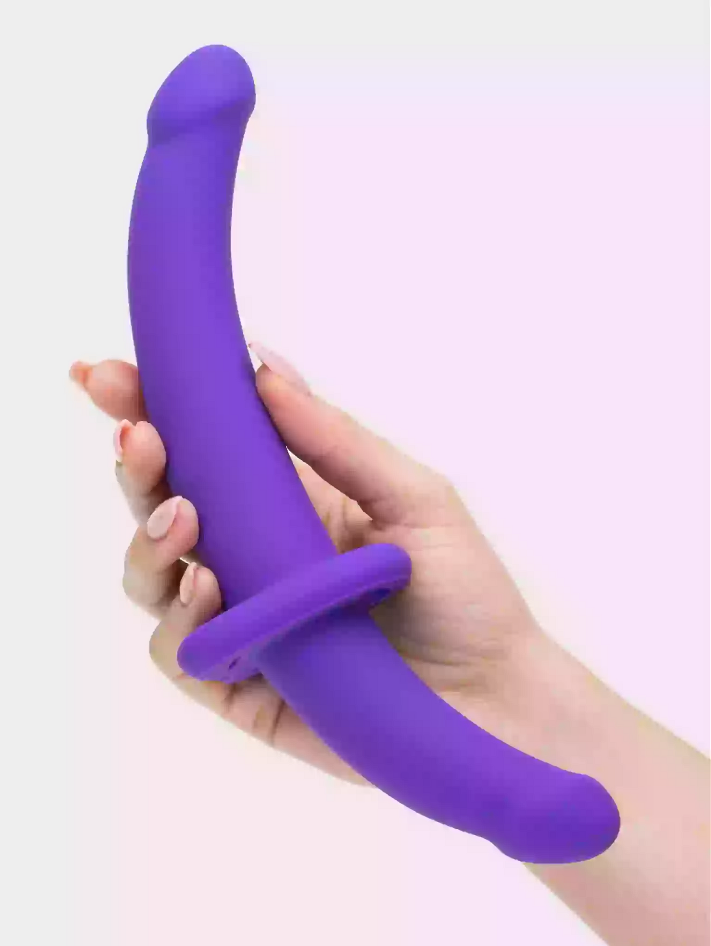 Purple silicone ring held in a hand against a light purple background