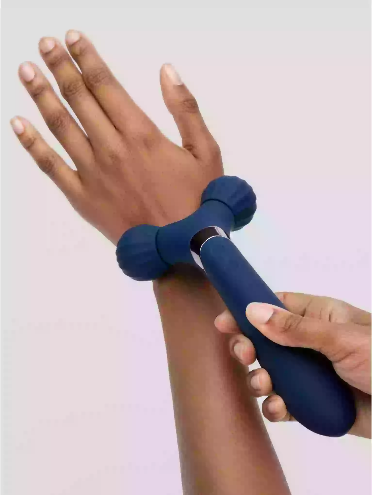 Hand using a blue massage roller on another hand against a light background
