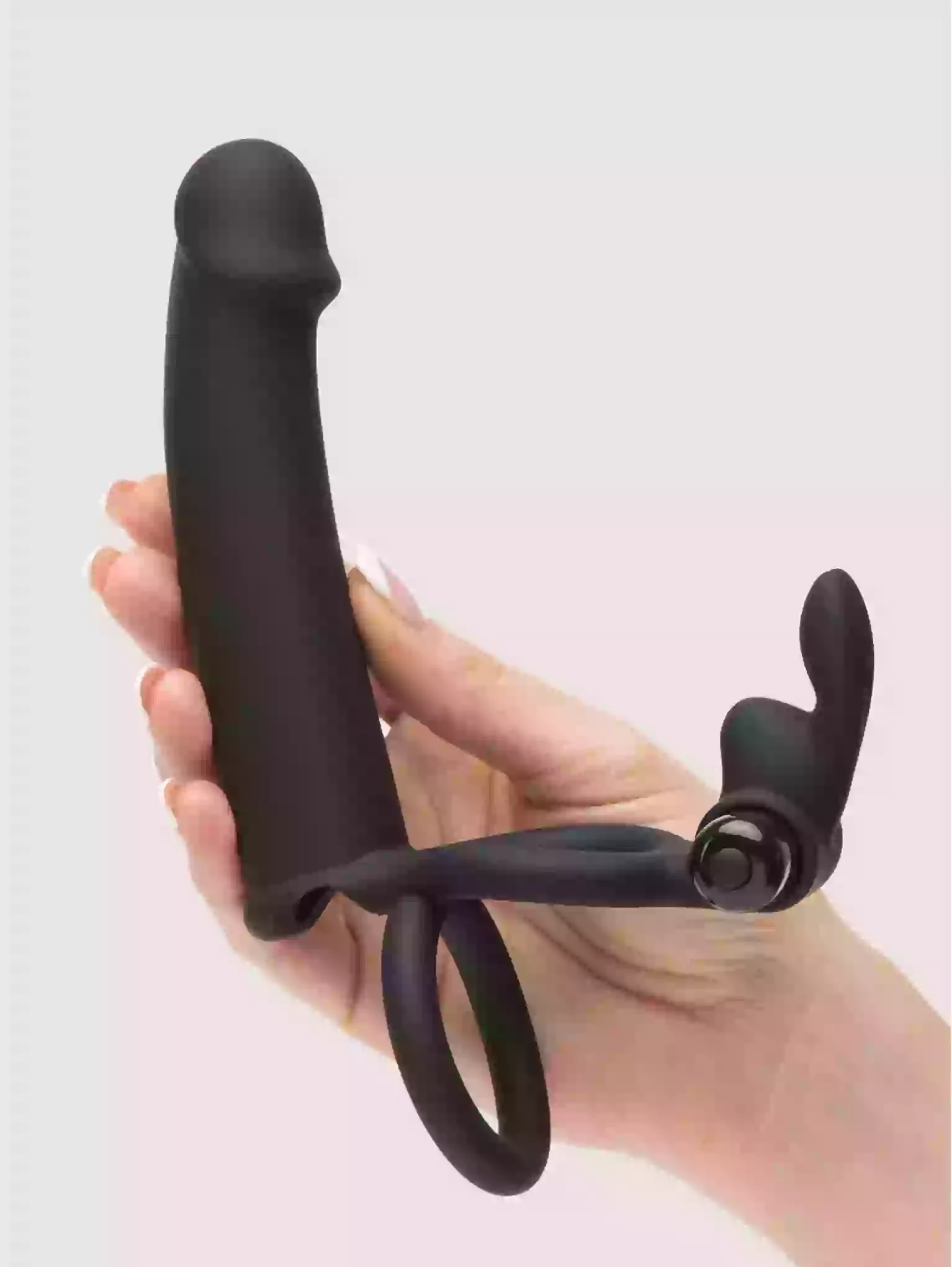 Black handheld device with a curved handle and adjustable straps held by a hand against a light background