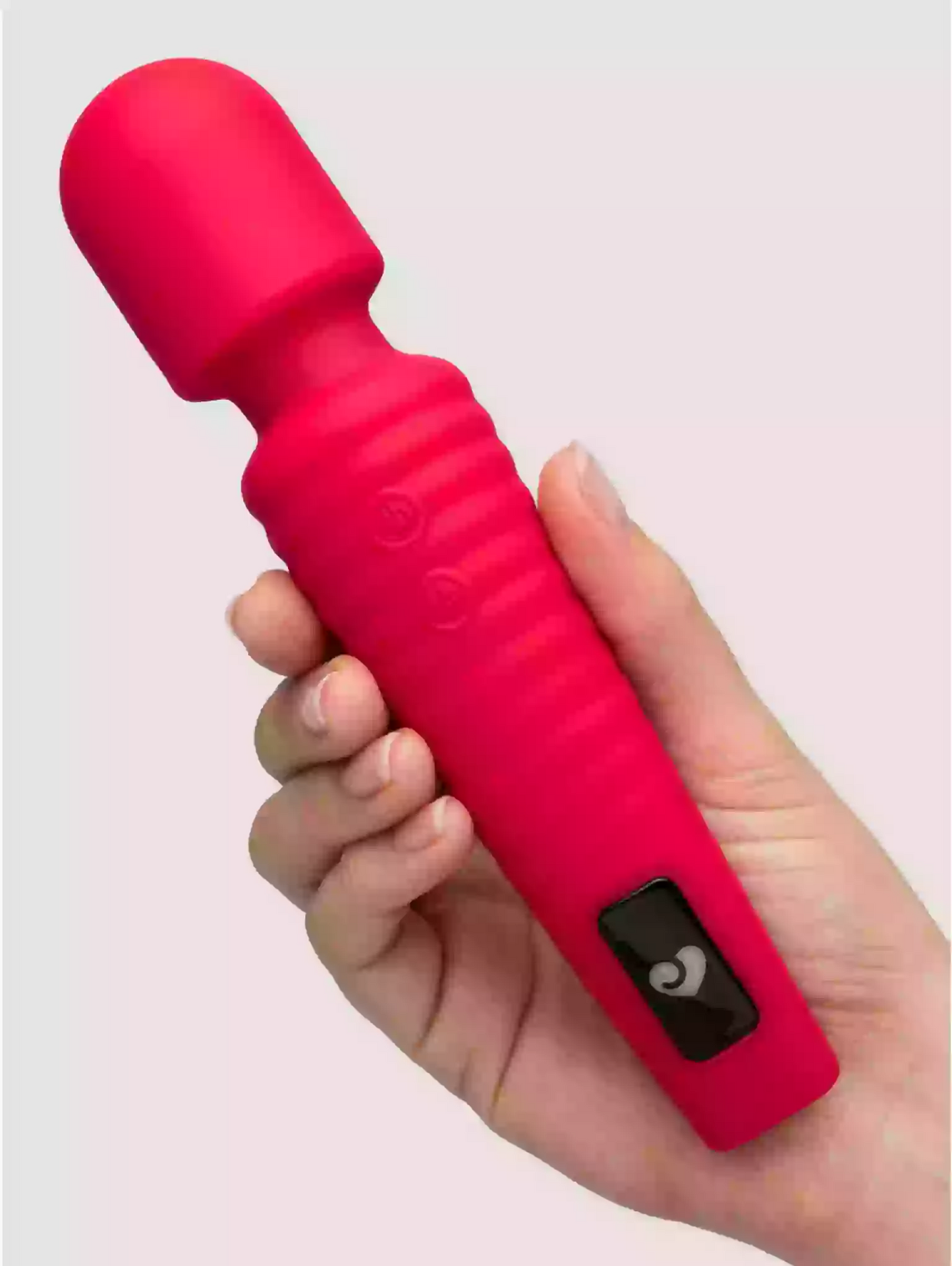 Red silicone wand massager held in a hand against a light pink background