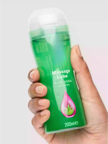 Hand holding a bottle of massage lube labeled 'Aloe Vera' on a light background