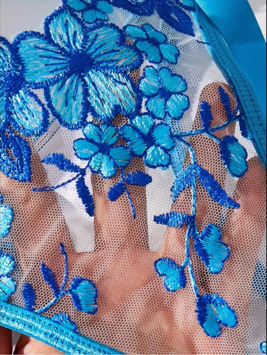 Close-up of blue floral embroidery on a sheer fabric background