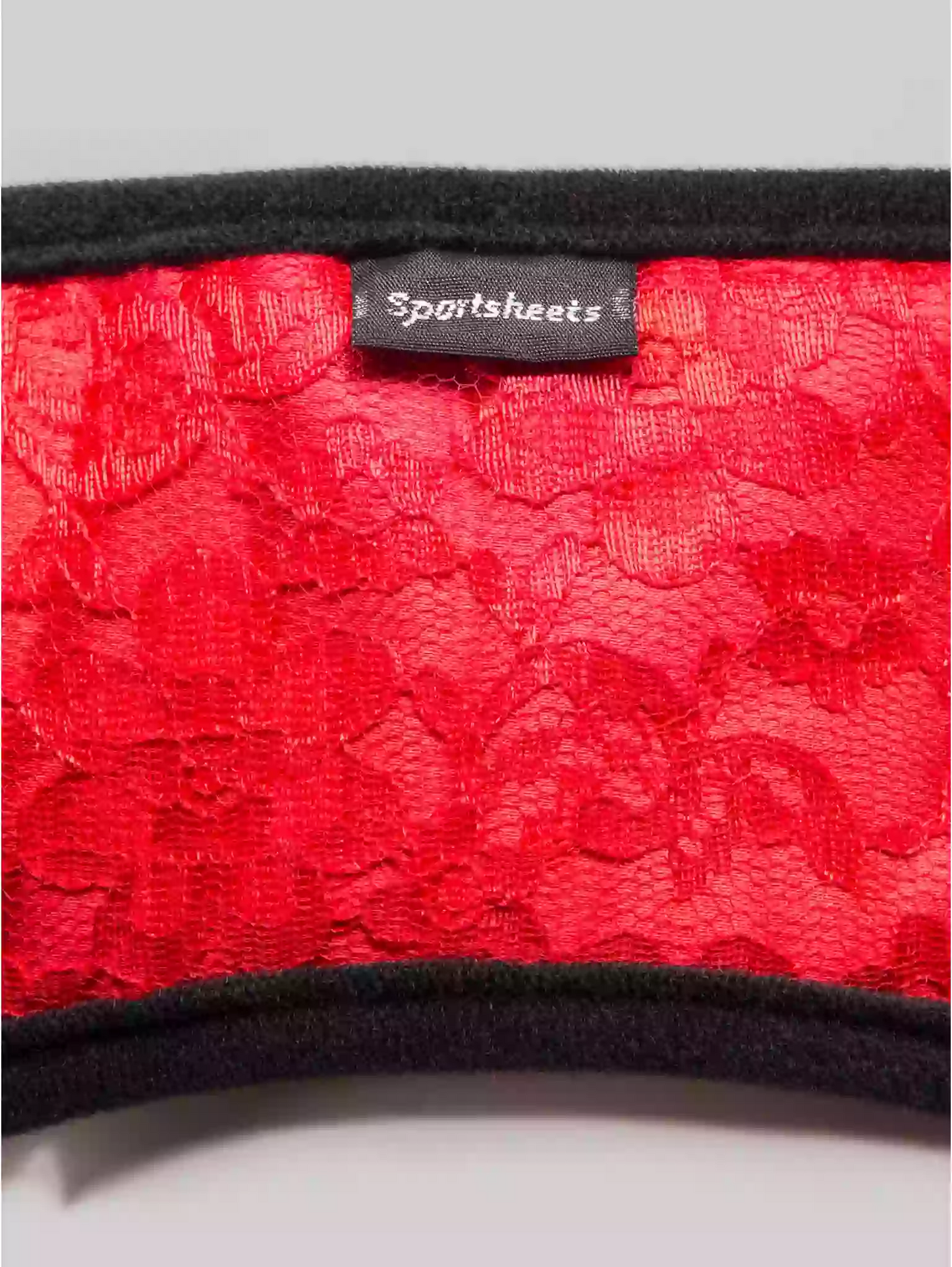 Red lace fabric with a 'Sportsheets' label on a gray background